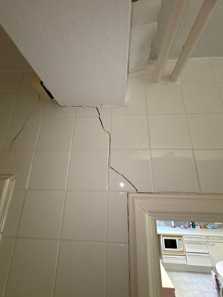 Crack running through internal wall tiles and door frame junction